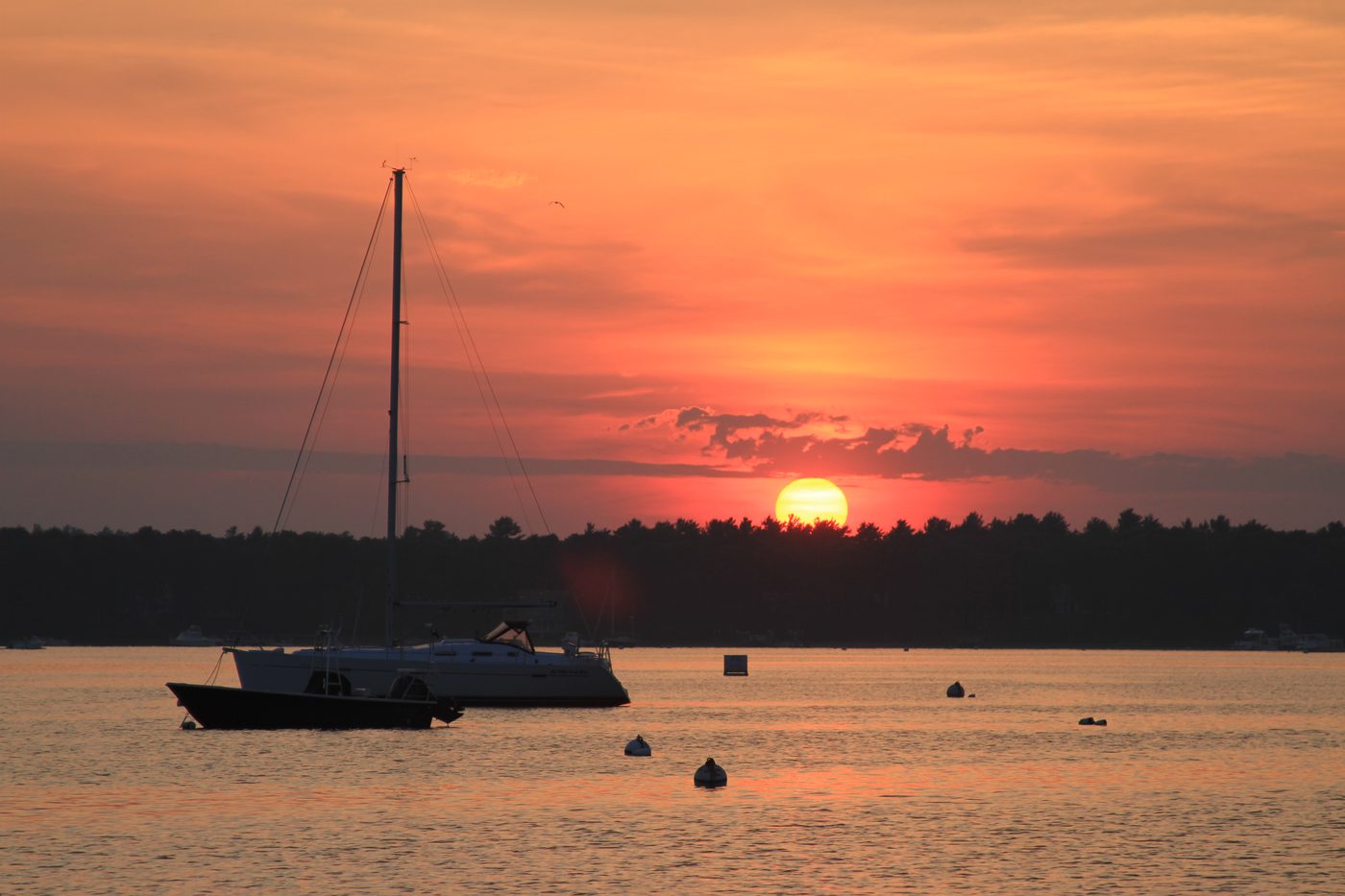 Fiery sunset over Osterville harbor with sailboat silhouette
